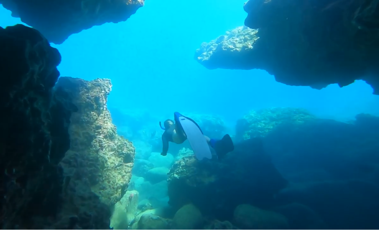 diver exploring underwater rocky terrain with clear blue water